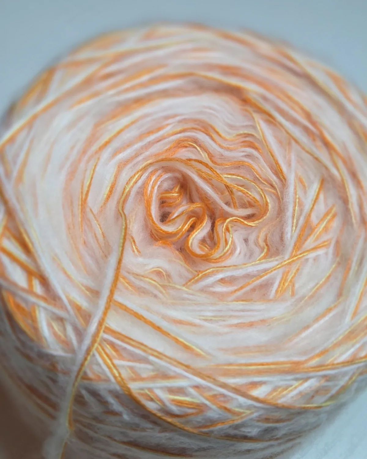 Garn-Bobbel „Apricotwolke“ von oben: weiche Fäden in Weiß, Apricot und Orange